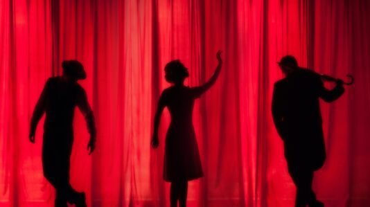 Actors on stage, red curtain, posing