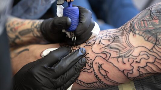 Artist doing a tattoo in human arm