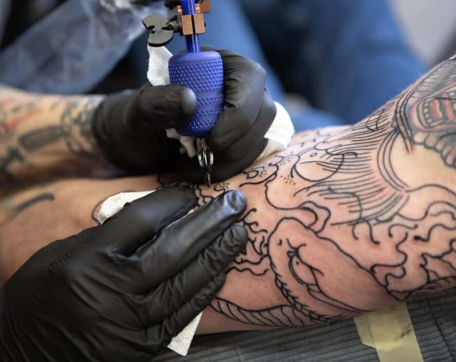 Artist doing a tattoo in human arm