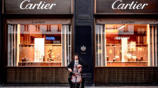 Musician playing Cello instrument in front of Cartier Store