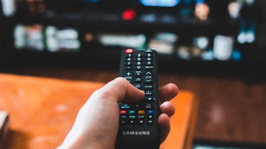 person holding a black tv remote control