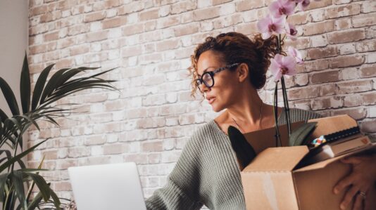 woman with eyeglasses carrying a box