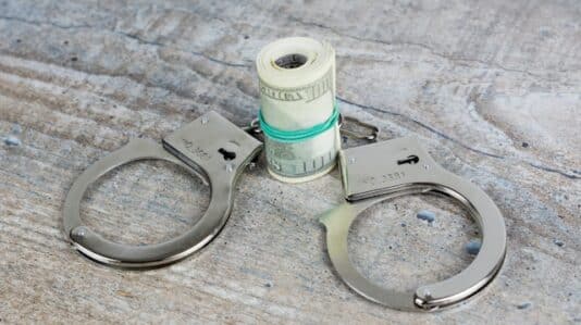 Handcuffs and US dollars on wooden background