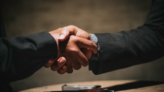 shaking hands over a gun