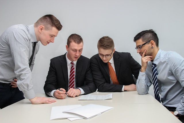 4 men looking at a document