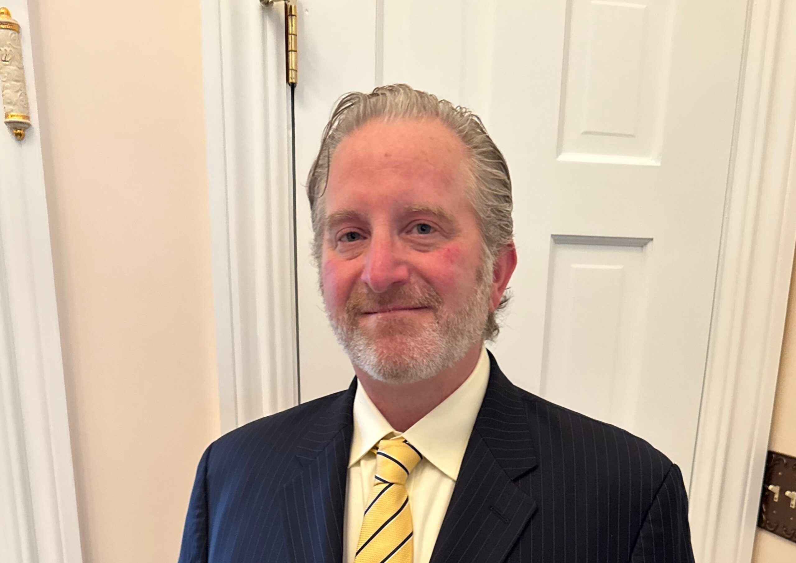 a man wearing black suit and yellow tie