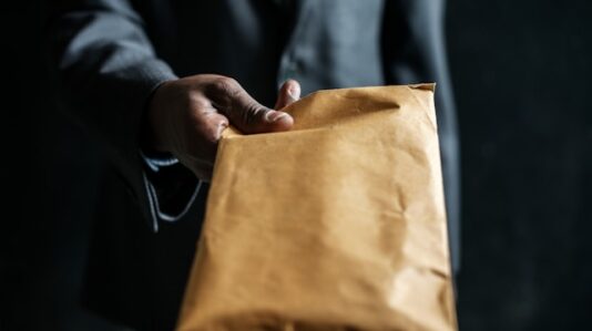 a man handing a brown envelope