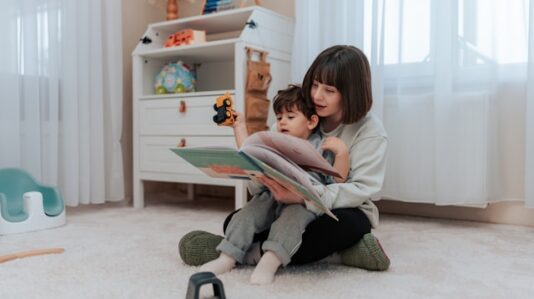 a woman showing a story book to a toddler