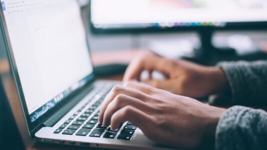 a person's hand typing on a laptop
