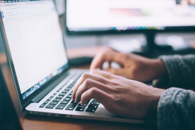 a person's hand typing on a laptop