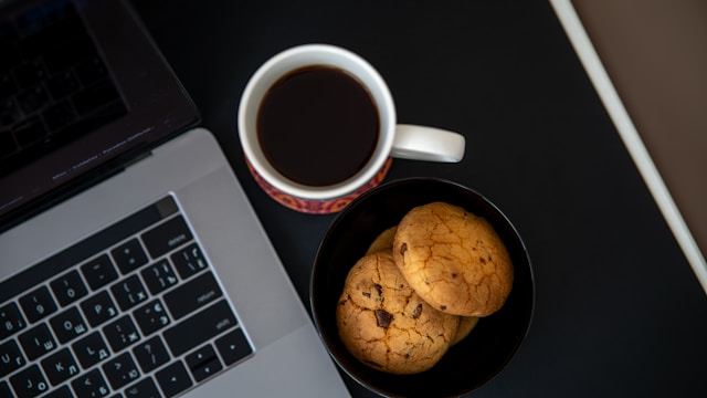 cup of coffee and cookies next to a laptop