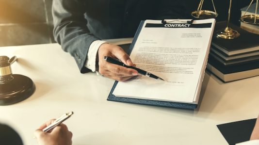 a document in a clipboard and a ballpen pointing on signature line